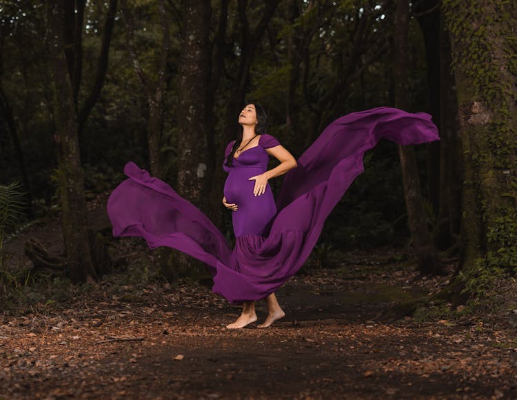 A Pregnant Woman In Purple Flowing Dress