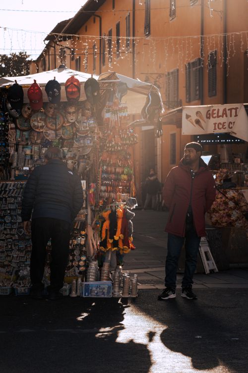 Free Street vendors in a busy Pisa market showcasing authentic Italian souvenirs under the afternoon sun. Stock Photo
