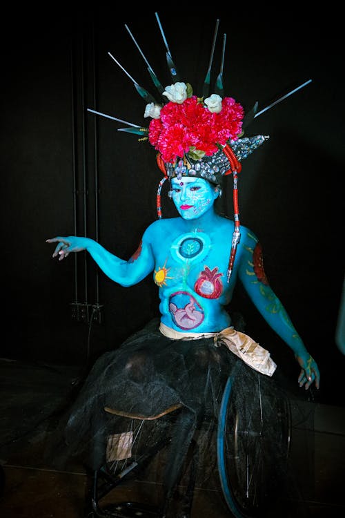 A woman in blue body paint with flowers on her head