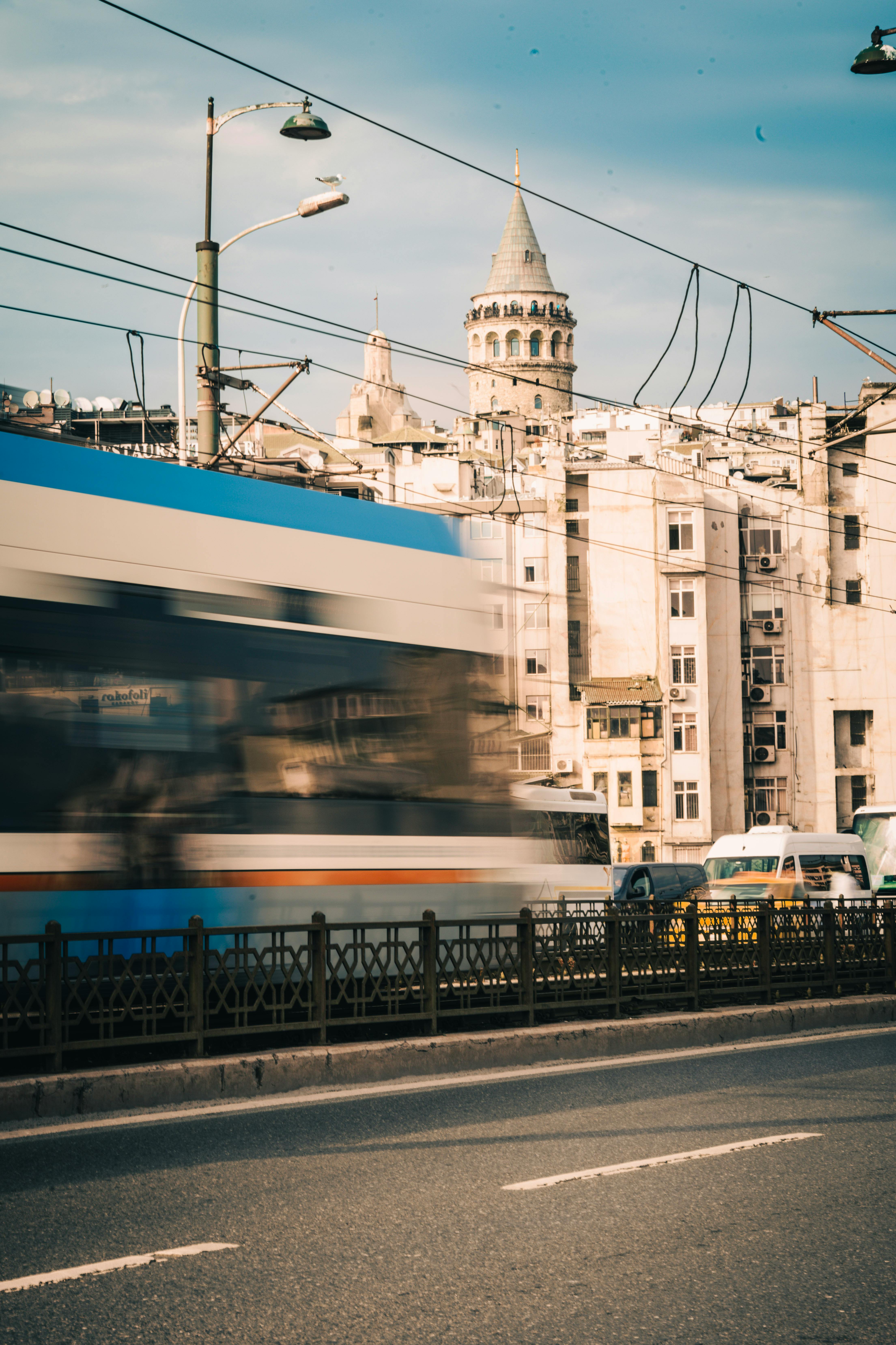 A dynamic city street view with a blurred tram and the historic Galata Tower in Istanbul.