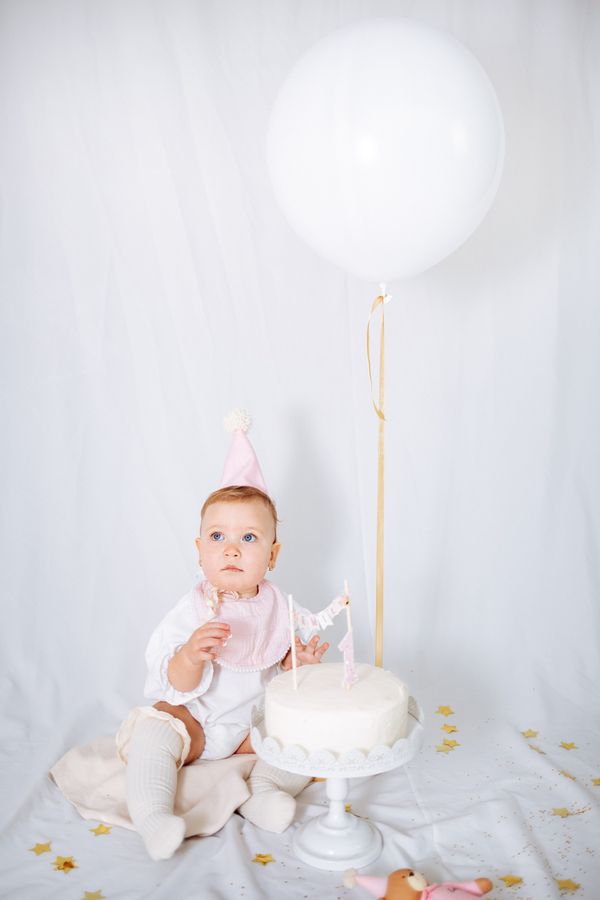 Baby with balloons and birthday cake