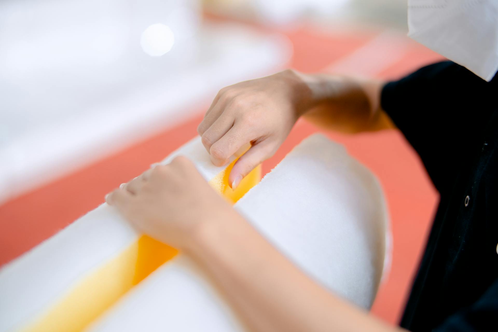 Close-up of a person manipulating polyurethane foam, showcasing detailed handwork in an industrial setting.