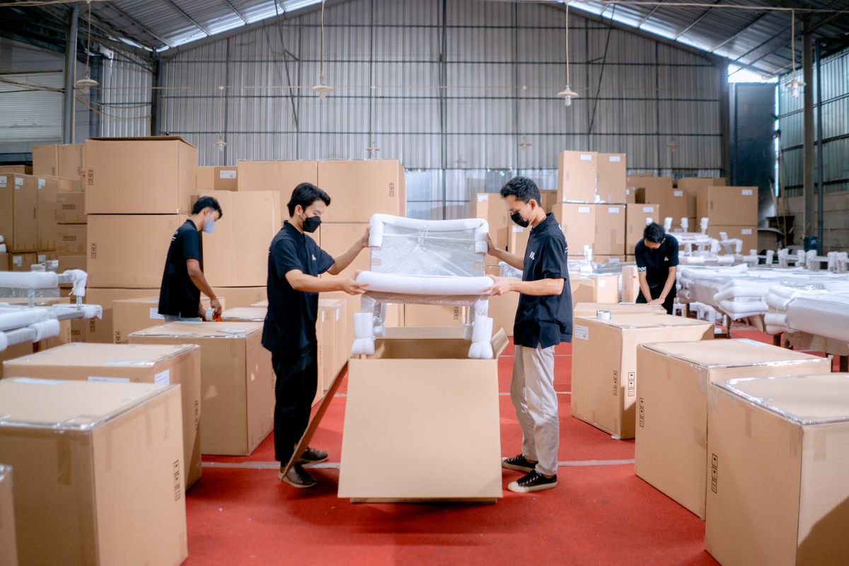 Workers packing a chair into a protective shipping carton