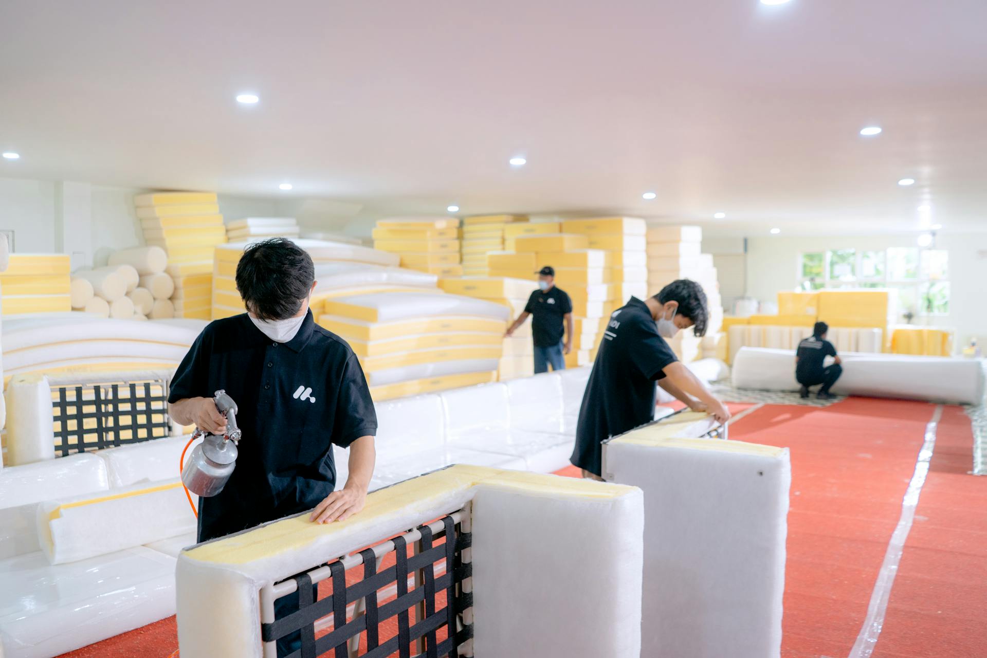 Employees crafting furniture in a workshop, focusing on cushion assembly and quality control.