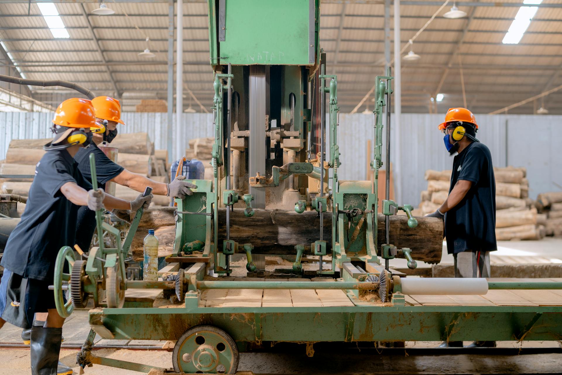 Industrial lumber processing with workers operating machinery in a factory setting.