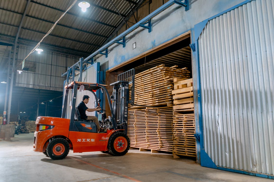 An operator lifting a stack of wooden pallets with a forklift