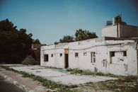 Dilapidated structure in Kuwait City, showcased with nearby vegetation and a clear blue sky.
