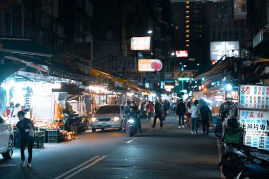 A lively night scene at a busy city market, with people exploring illuminated stalls.
