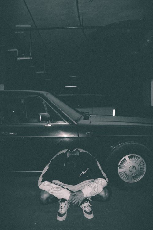 Free Black and white photo of a man squatting by a vintage car in Muscat, Oman. Stock Photo
