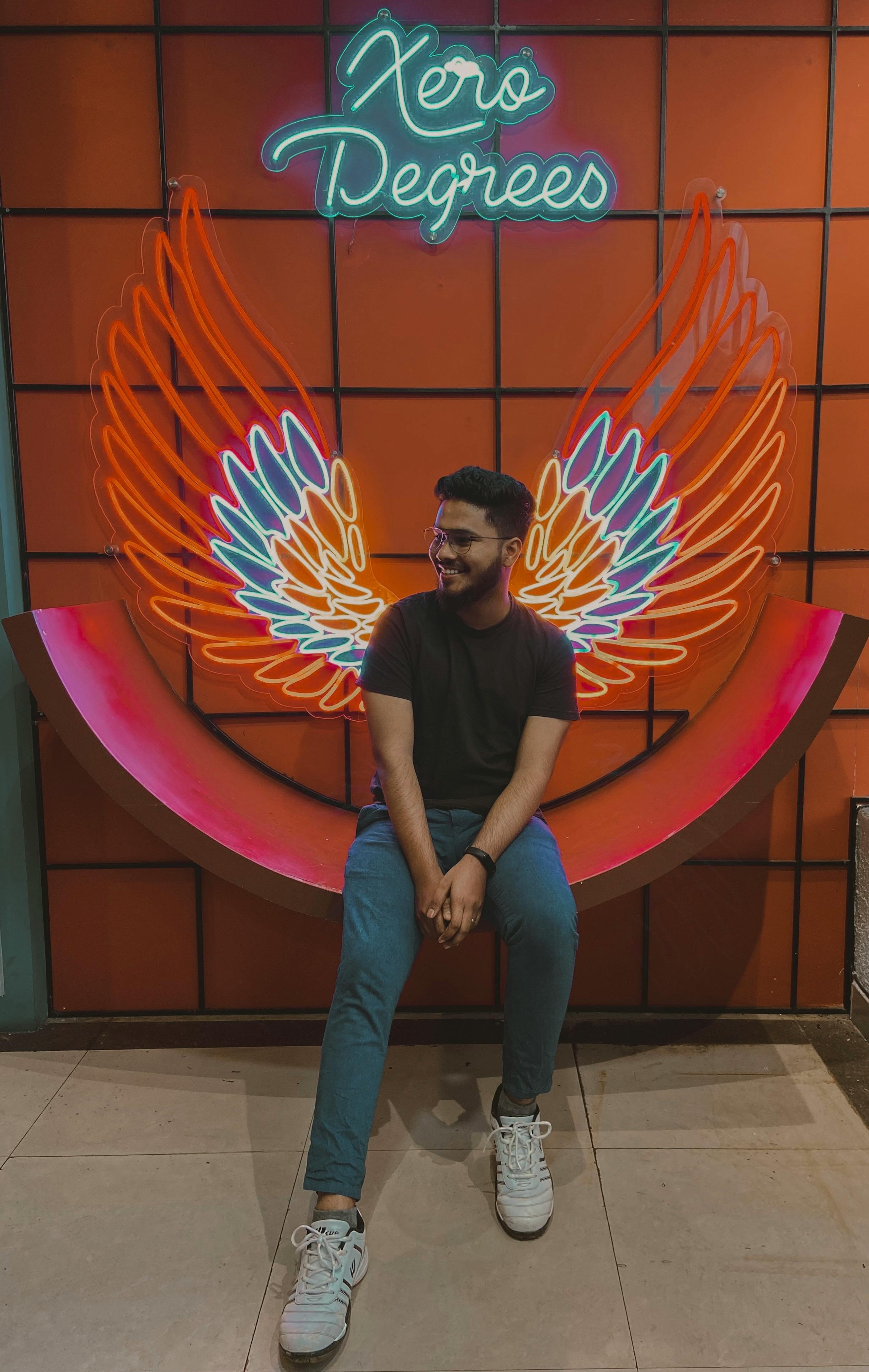 smiling man sitting on bench near neon wings