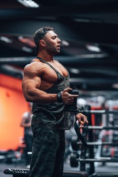 A muscular man in a gym lifting weights, focused on strength training.