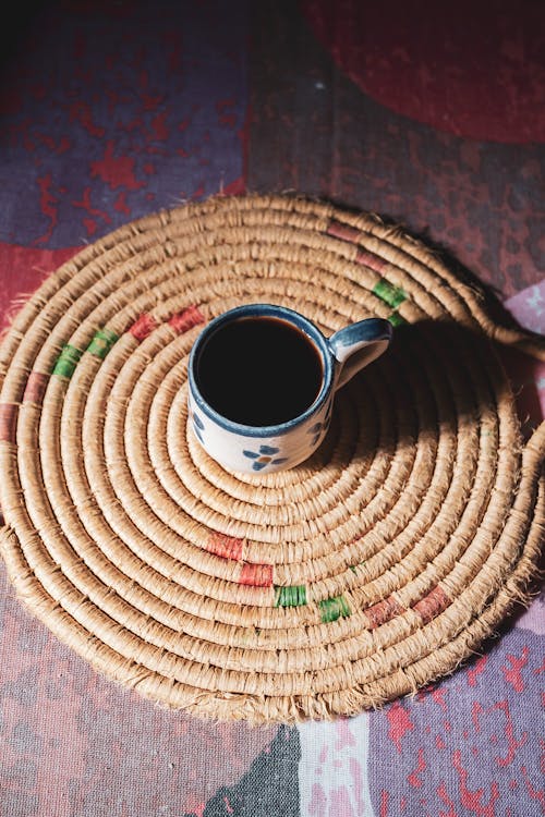 Free A coffee cup on a woven mat on a table Stock Photo