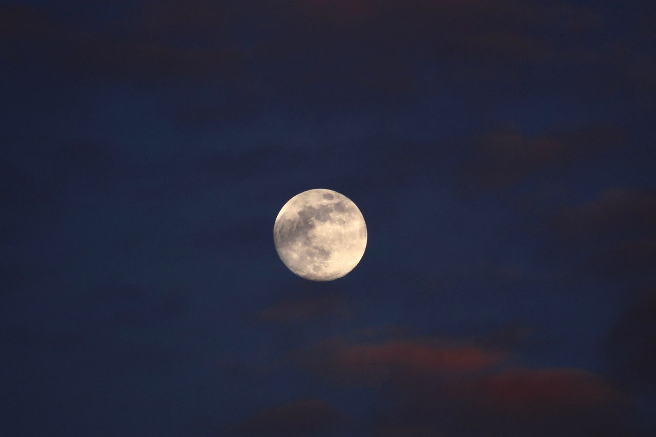 beautiful full moon against a dark cloudy night sky offering a serene
