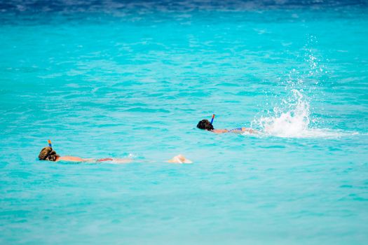 Two people snorkeling in crystal clear turquoise waters enjoying a tropical getaway.