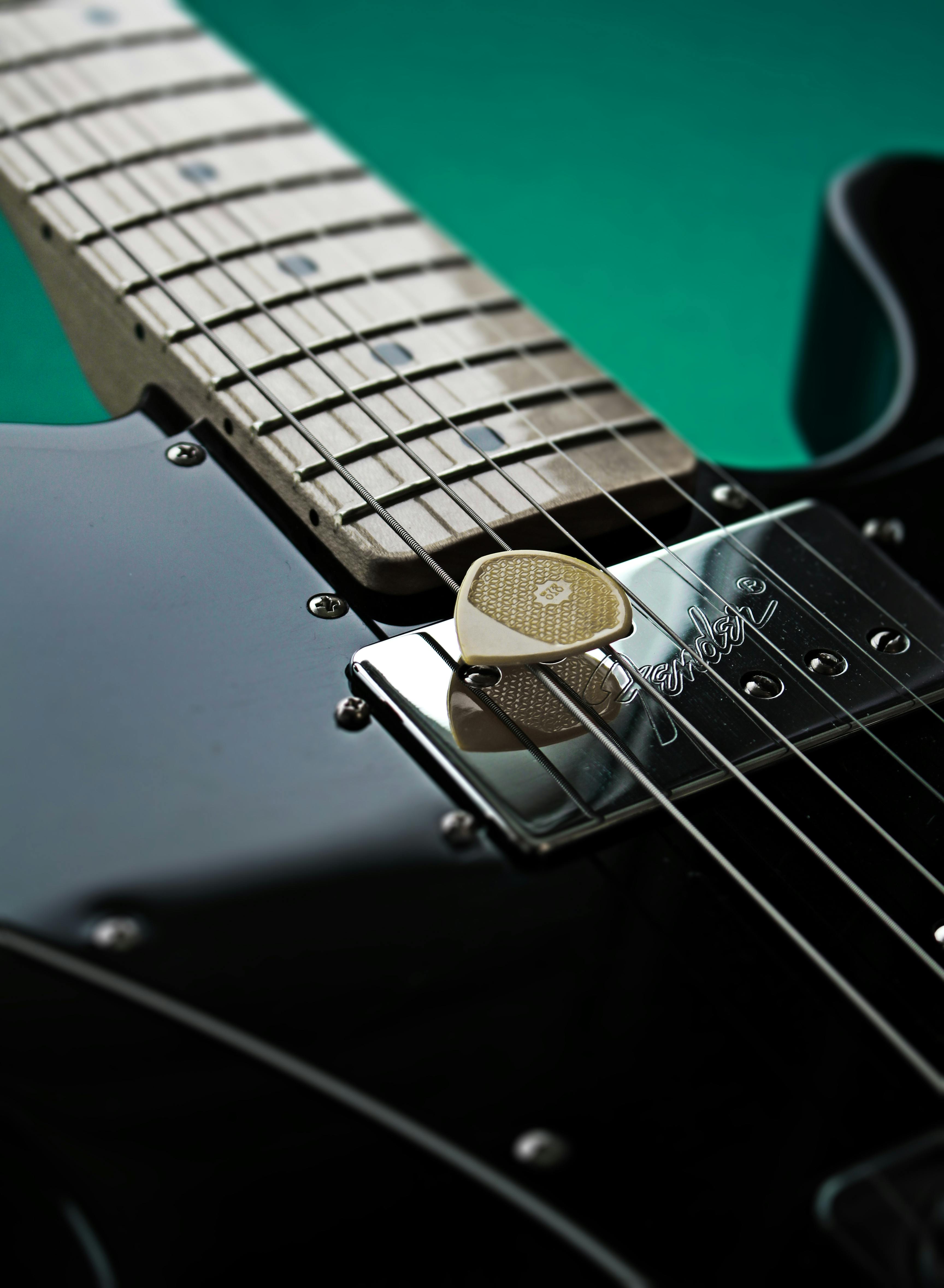 small pointy jazz guitar pick and a black electric guitar · Free Stock