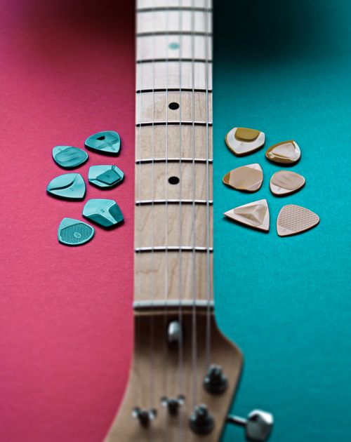 Free Close-up of an electric guitar neck with colorful picks on a split pink and teal background. Stock Photo