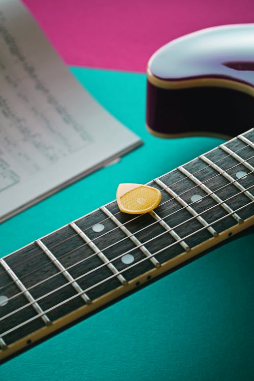 Close Up Photo of Yellow Plectrum on Electric Guitar