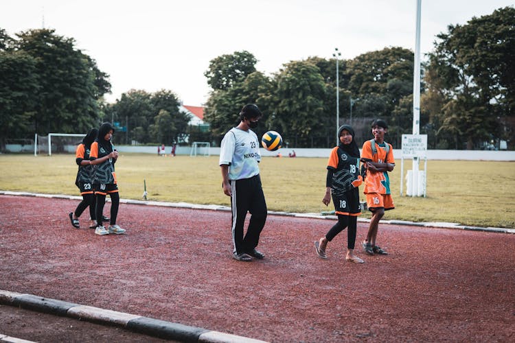 People Walking With Ball On Track On Sports Ground