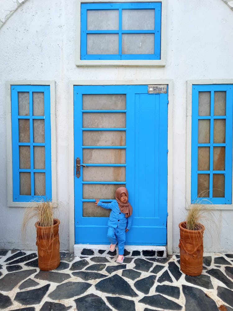 Cute Girl Holding On Blue Door