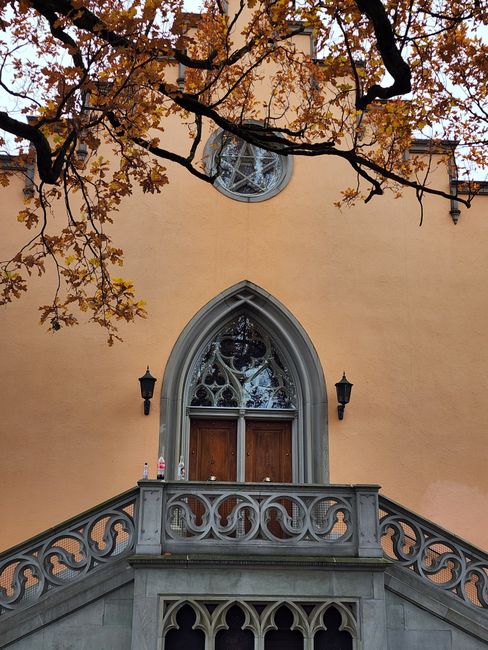 An elegant Gothic facade with autumn leaves framing the scene.