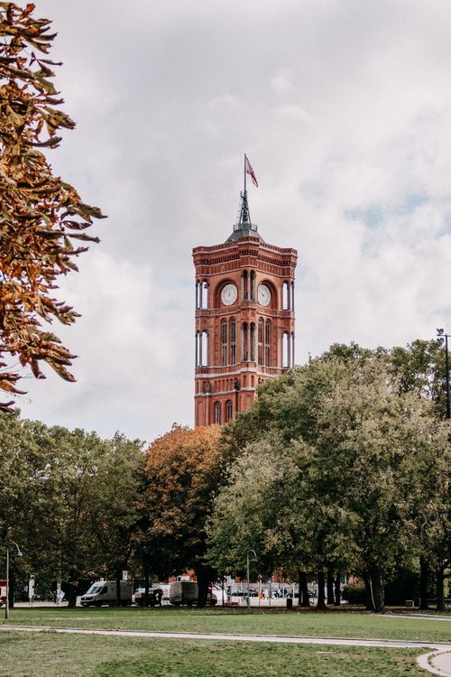 Free Rotes Rathaus clock tower surrounded by greenery in Berlin, Germany during fall. Stock Photo