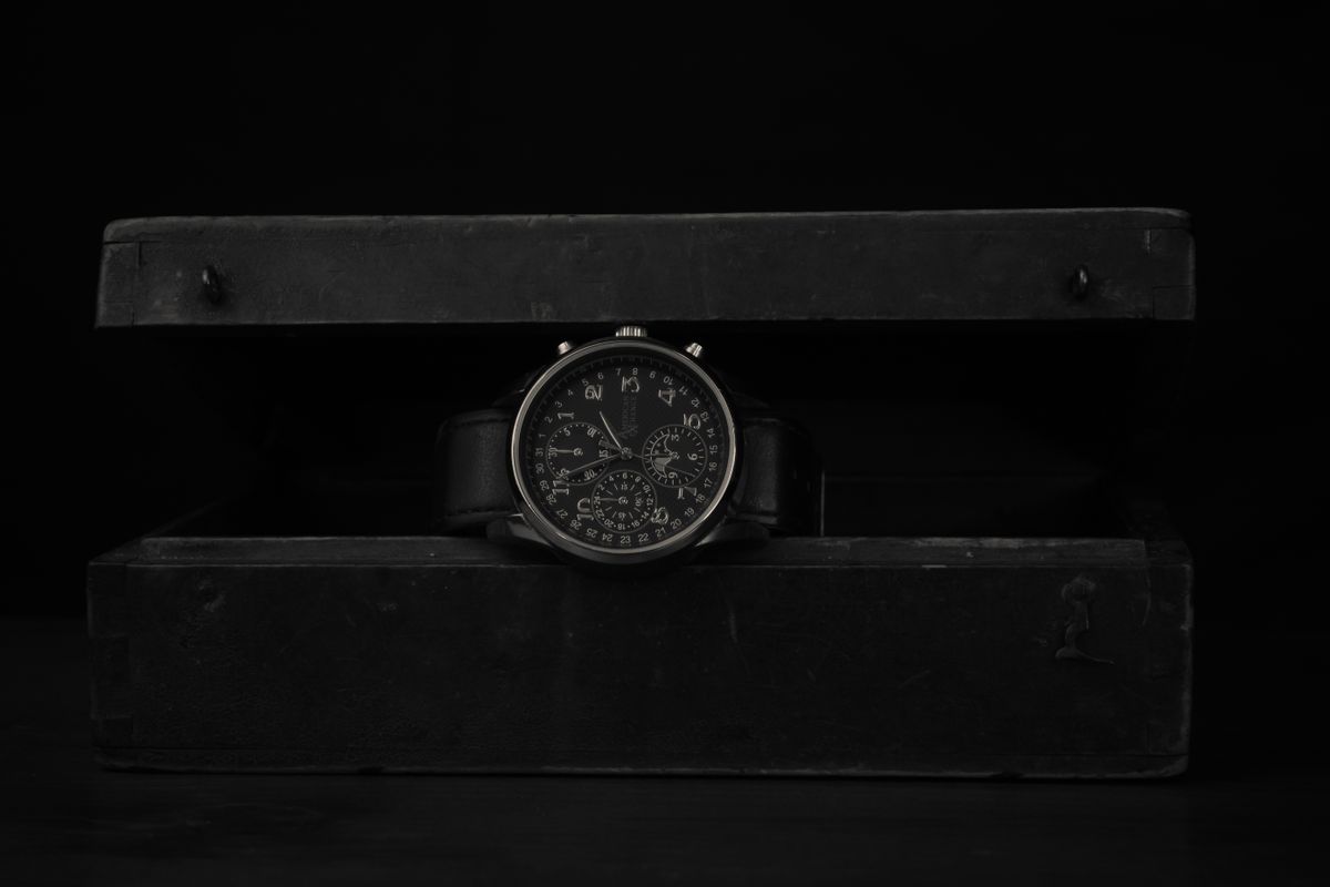 A black-dial dive watch resting in a wooden case — photo by PonerMas s on Pexels