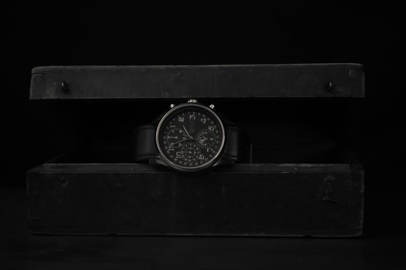 A black wristwatch displayed on a dark vintage box — photo by PonerMas s on Pexels