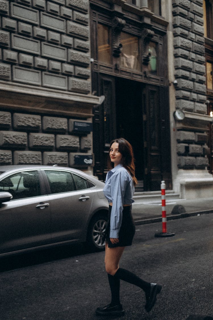 Woman In Blue Crop Shirt, Black Mini Skirt And High Socks Walking On A Street