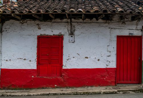 Free Charming rustic house facade with red doors and textured walls, perfect for architecture enthusiasts. Stock Photo