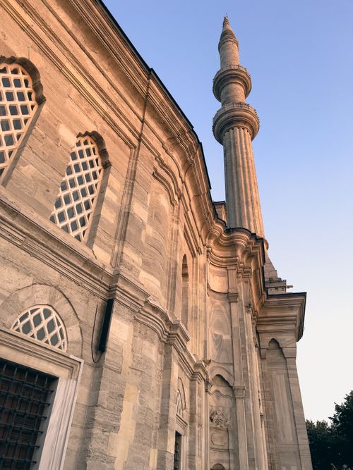 Free Exterior view of a mosque with a minaret showcasing Ottoman architecture in Istanbul at sunset. Stock Photo