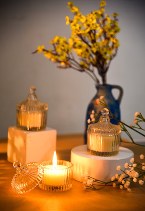 Candles Burning near Flowers on Table
