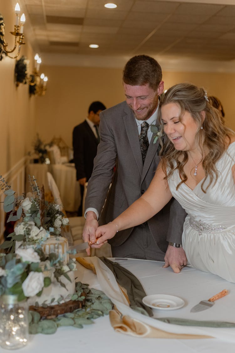 A Bride And Groom Cutting A Cake Together