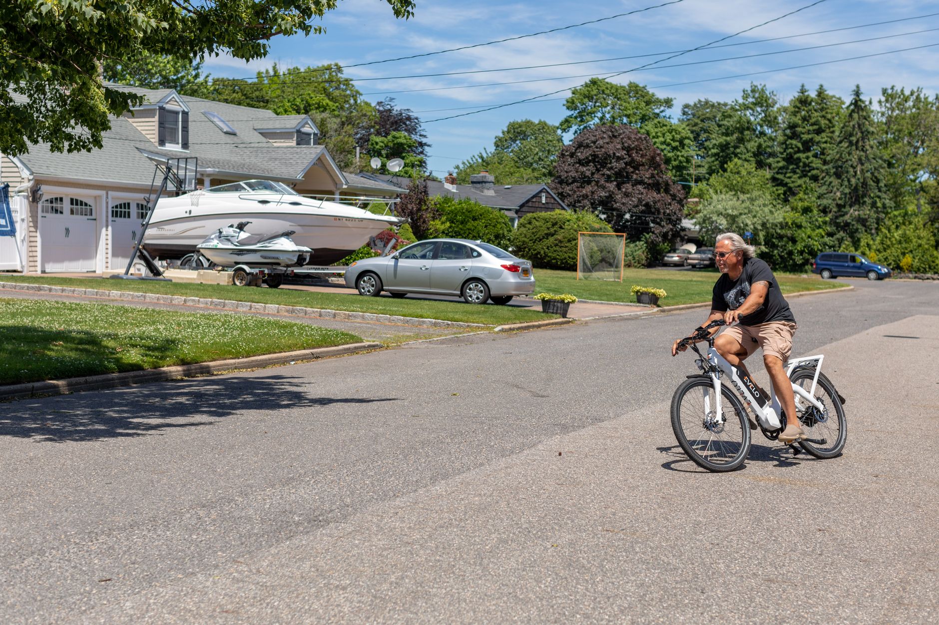 A man enjoys a ride on an electric bike in a suburban street on a sunny day.