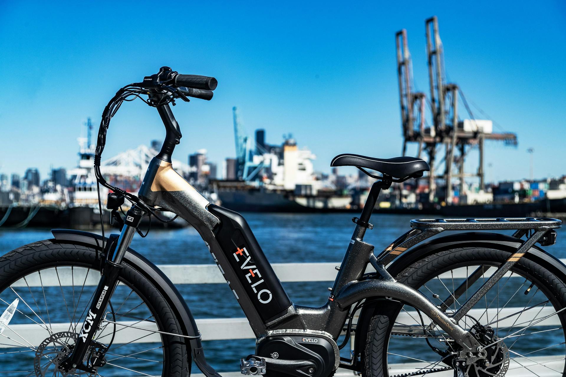 A black electric bike parked on the dock by the water