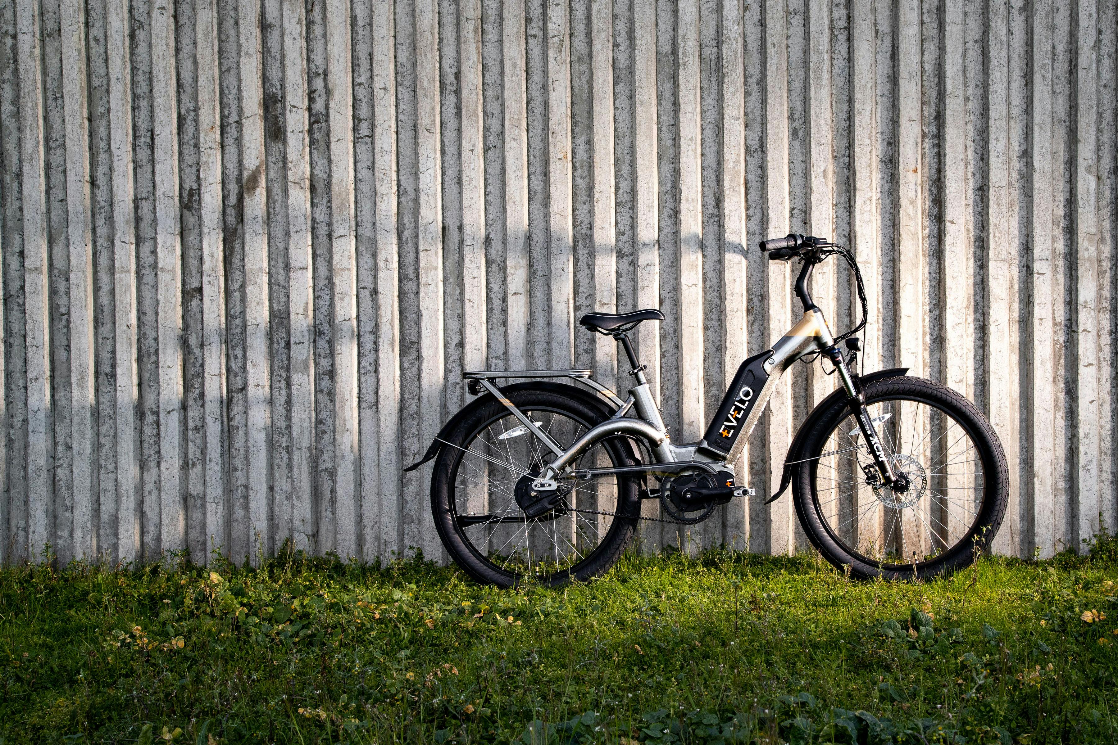 Free A sleek Evelo electric bike resting beside a modern concrete wall on a sunny day in Seattle. Stock Photo