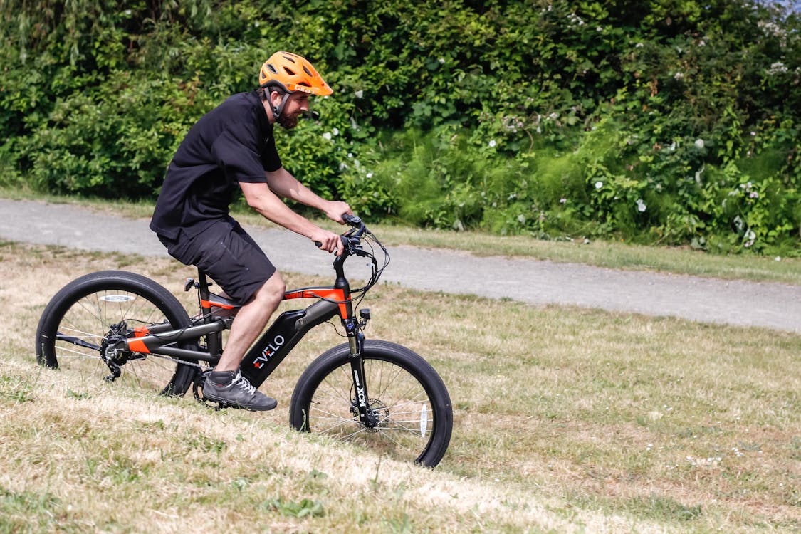 Man in Black Shirt and Shorts Riding a Bike on Grass Field 