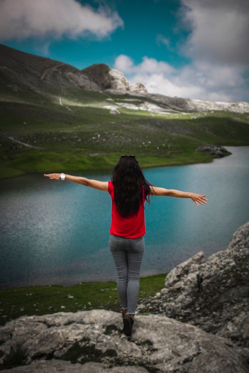 Free A woman in red admires scenic mountain lake views in Niğde, Türkiye. Stock Photo