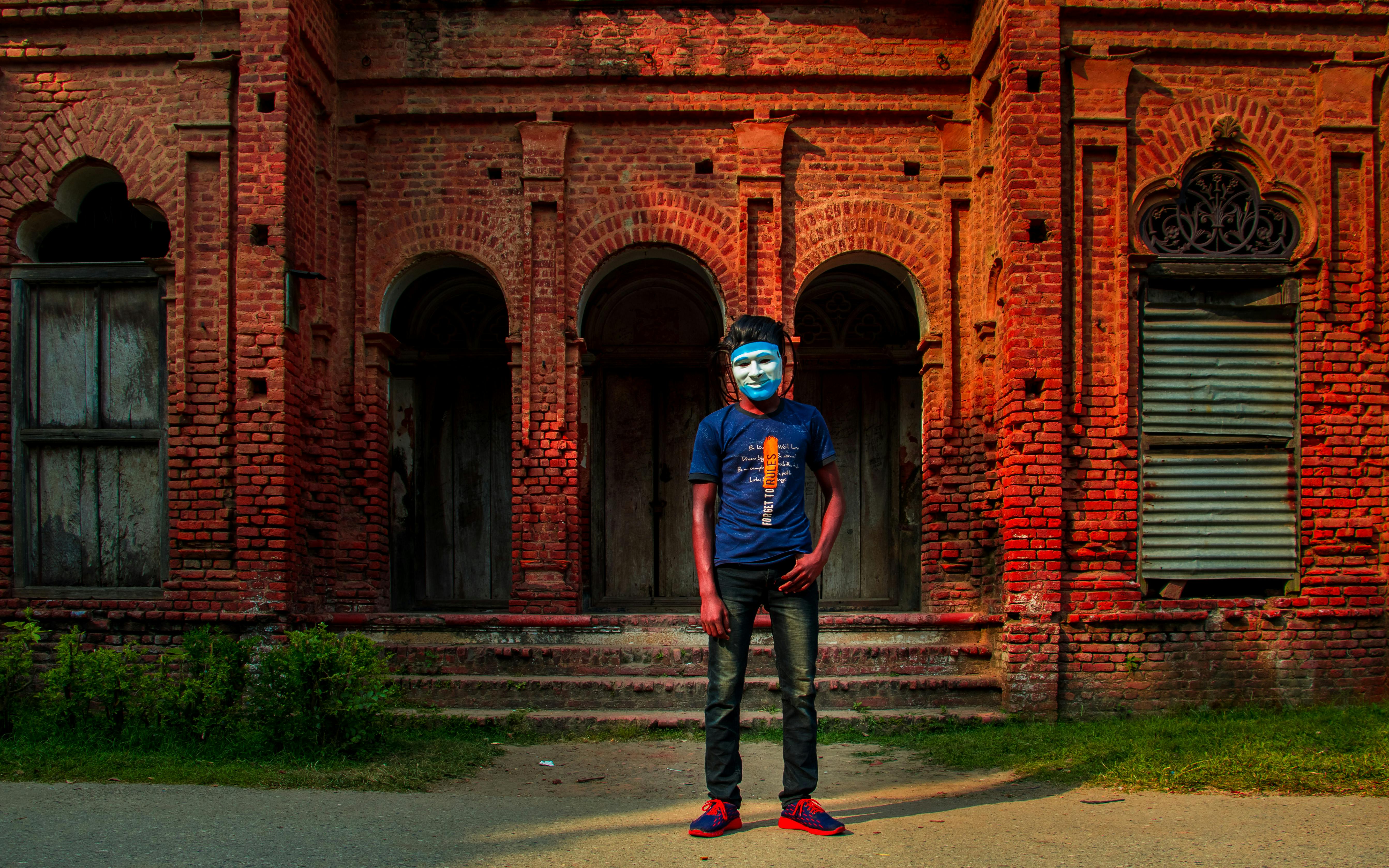 a man wearing mascara standing near red brick building