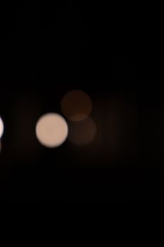 Abstract bokeh lights on a dark background create a soft and moody visual effect.