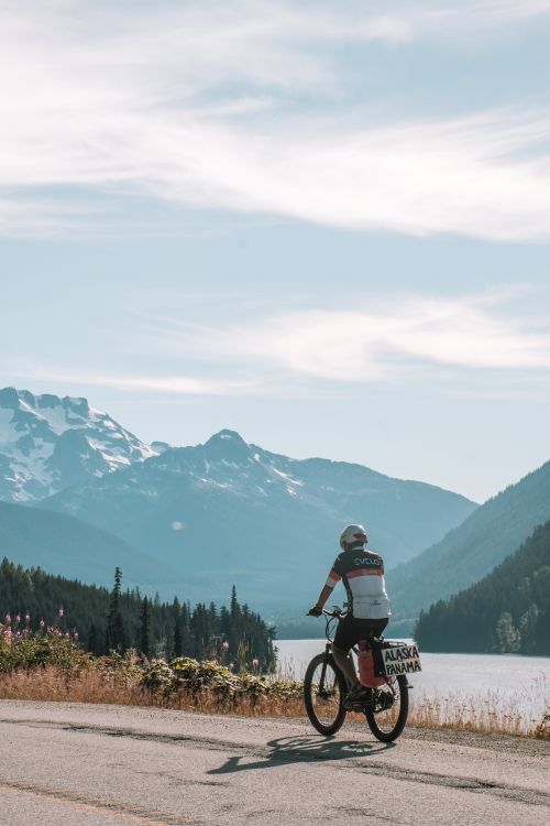 Free A cyclist enjoys a ride on a picturesque road in Vancouver with a mountain backdrop. Stock Photo