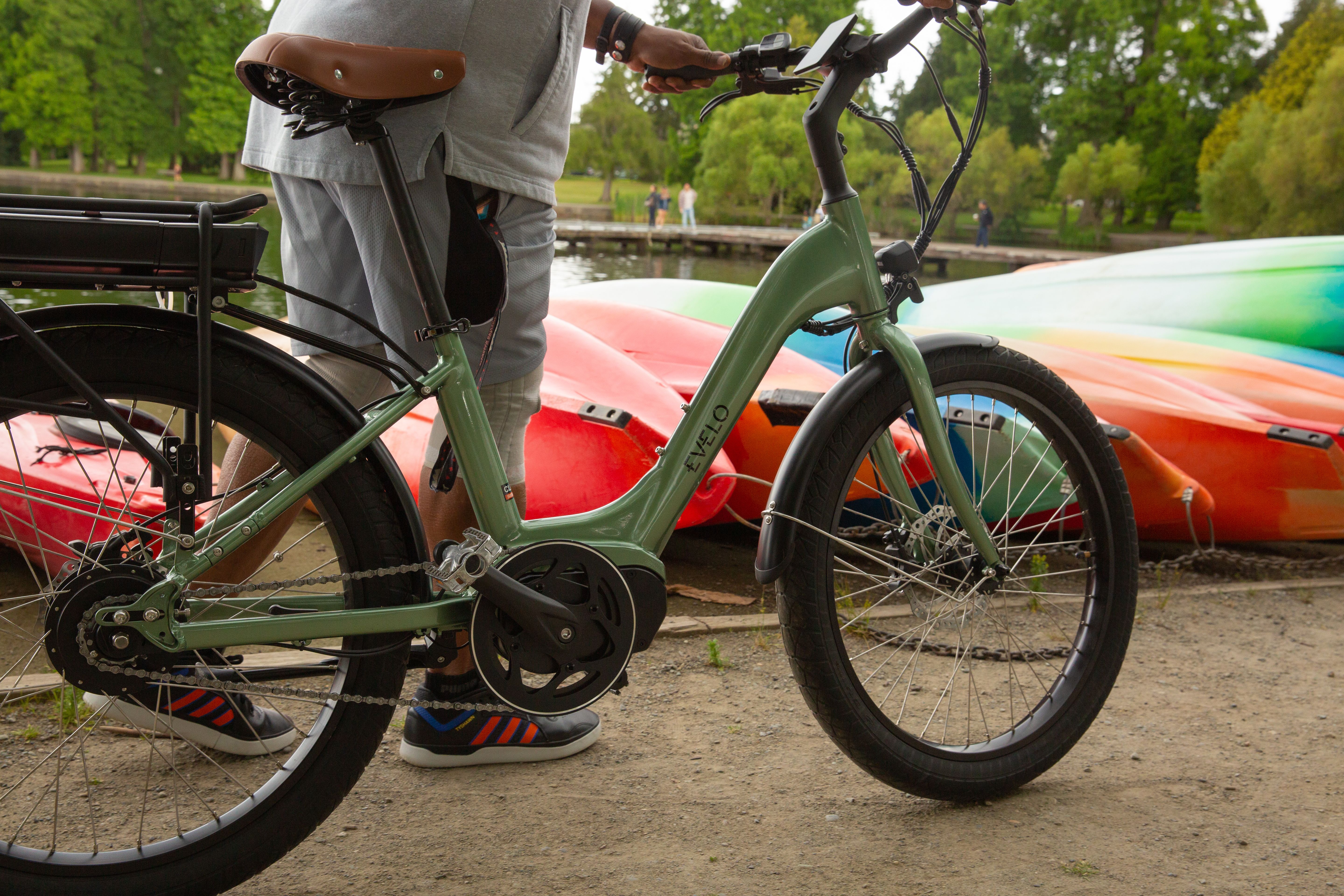 A man stands by a bike and vibrant kayaks in a park, Seattle.