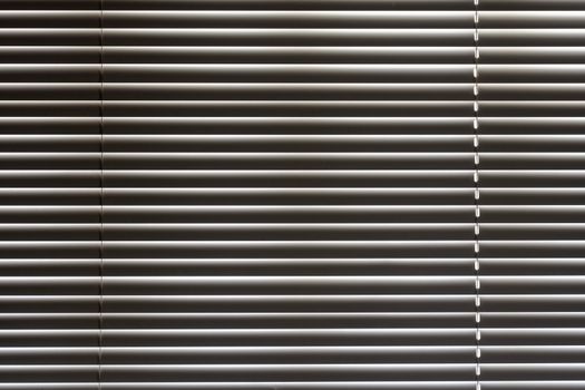 Minimalist close-up of sleek horizontal window blinds with metallic sheen.