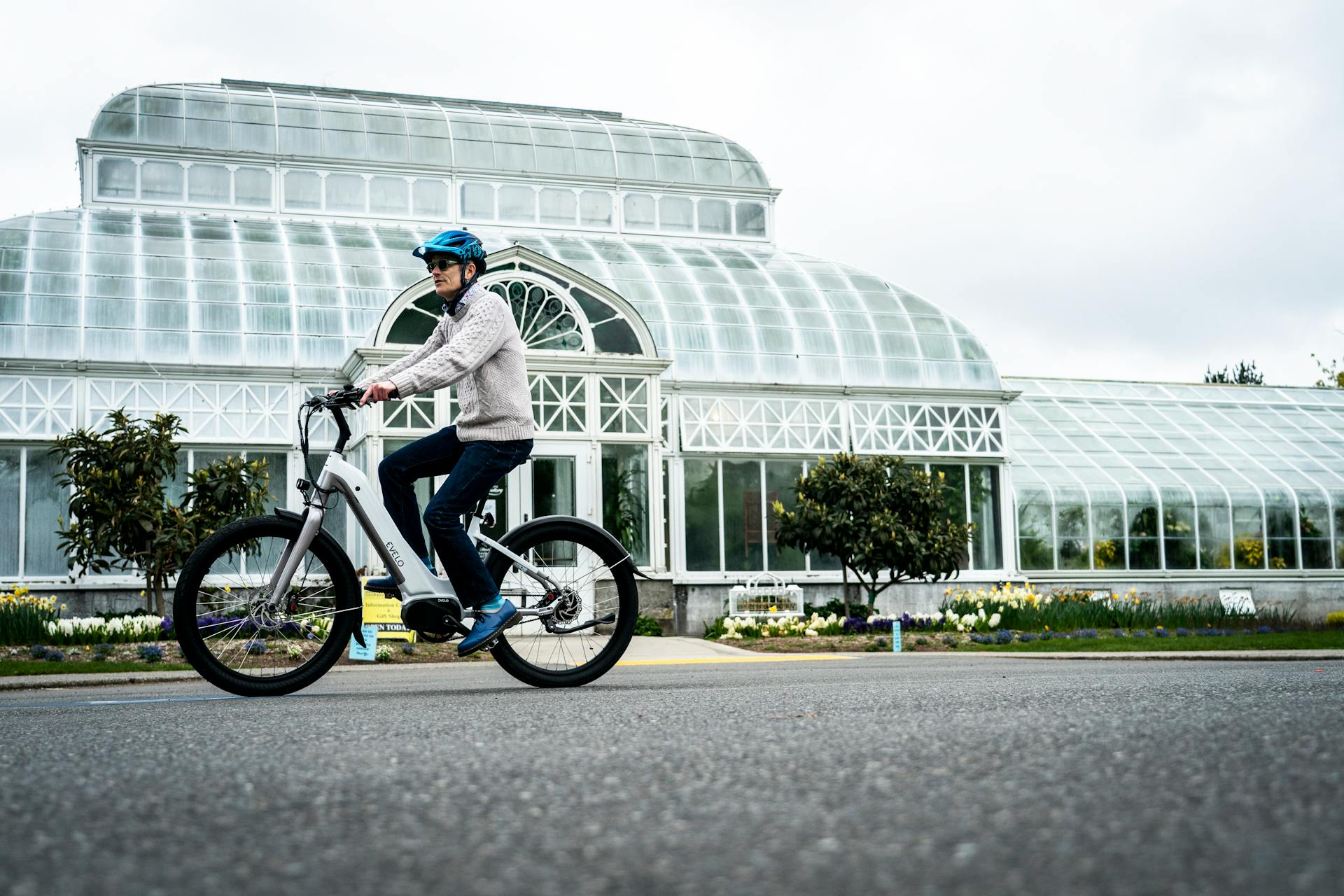 A person riding an electric bike in front of a greenhouse