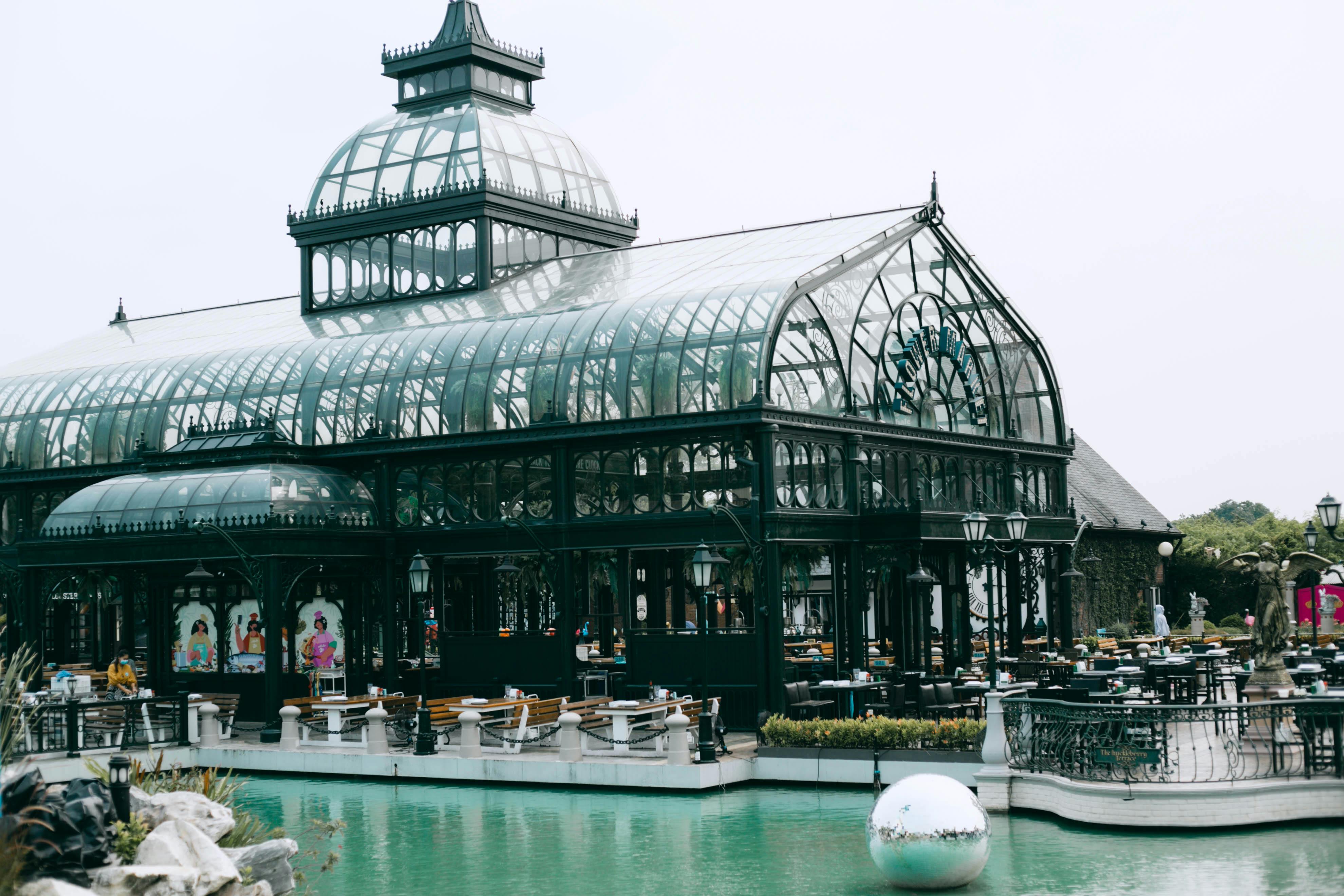 Elegant glass conservatory café beside a tranquil pool in Bangkok, Thailand.