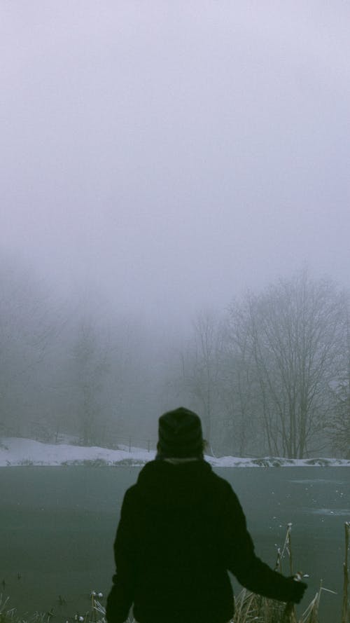 A Person Standing by a Lake in Winter 
