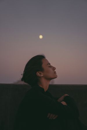 Person resting outdoors beneath the moon at dusk — photo by Bayram Musayev on Pexels