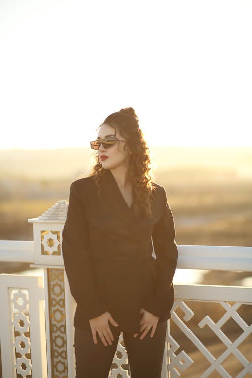 A Beautiful Woman in Black Long Sleeves Wearing Sunglasses while Looking Over Shoulder