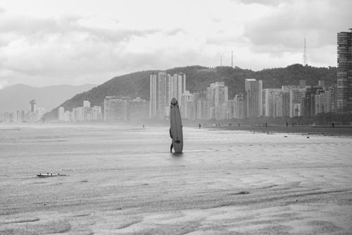 Free Monochrome image of a surfer at Santos beach, capturing modern skyline and waves. Stock Photo