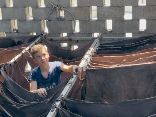 Free Young boy stands amid leather drying in Şehitkamil, Gaziantep workshop. Stock Photo