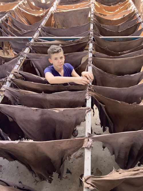 Free A boy stands amidst rows of drying leather in Gaziantep, Turkey. Stock Photo